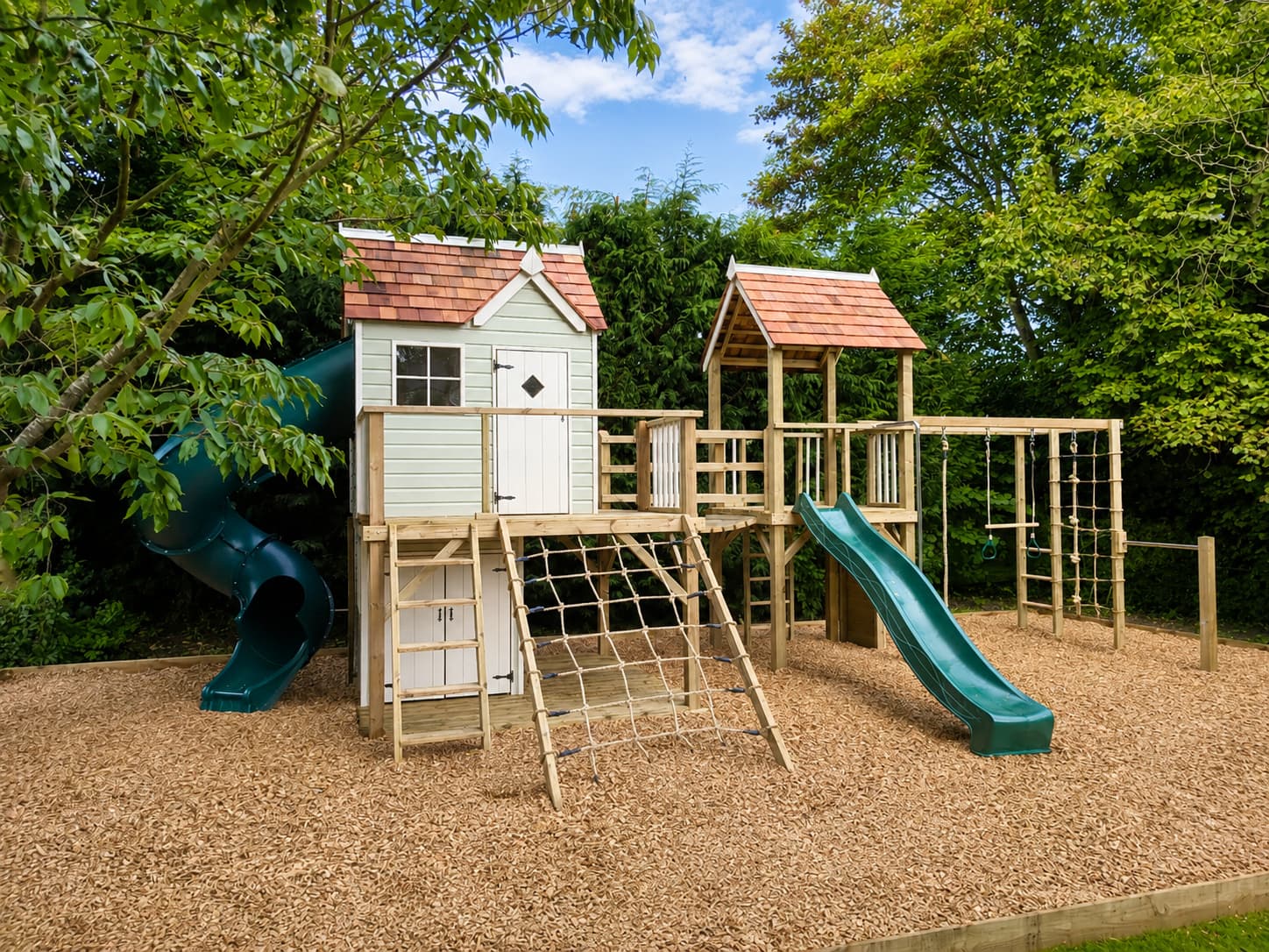 A Damson Mega Combo: the sage-green Real House cottage with cedar shingle roof, raised deck, tube slide, and second tower