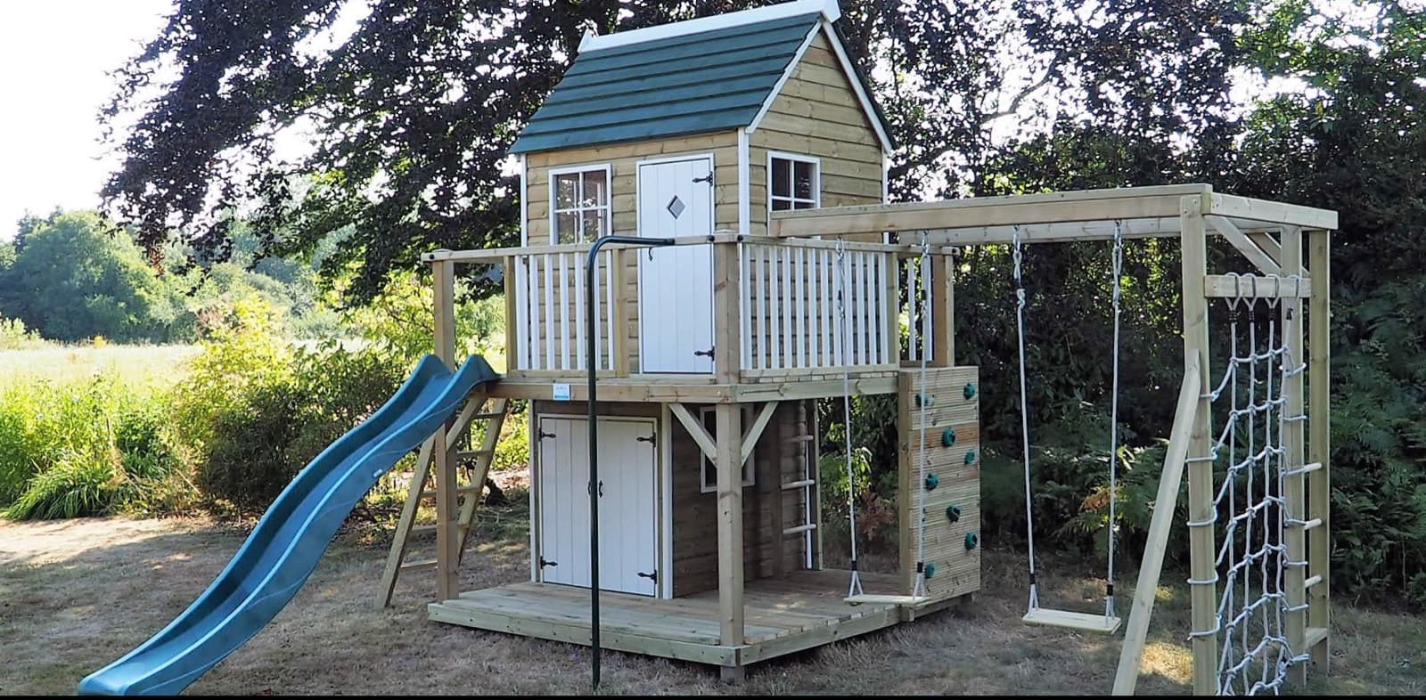 A Forest Mega: the Forest Playhouse raised over a lower deck and den with double doors and windows beneath