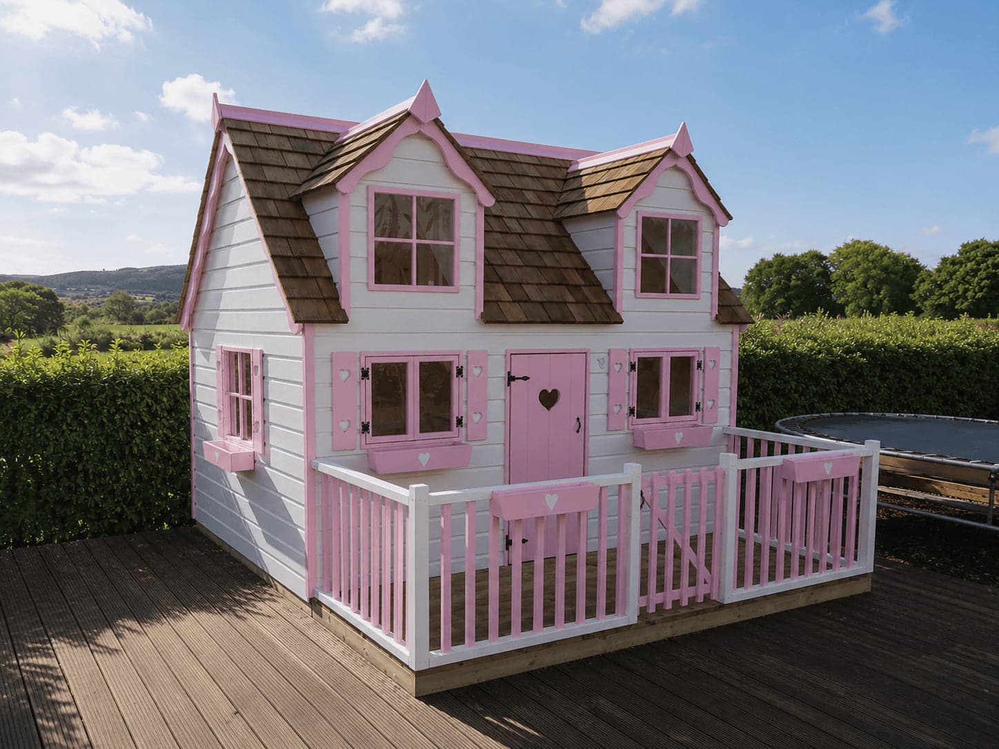 Harvestwood House designer playhouse with dormer windows, cedar shingle roof, and gated veranda on garden decking