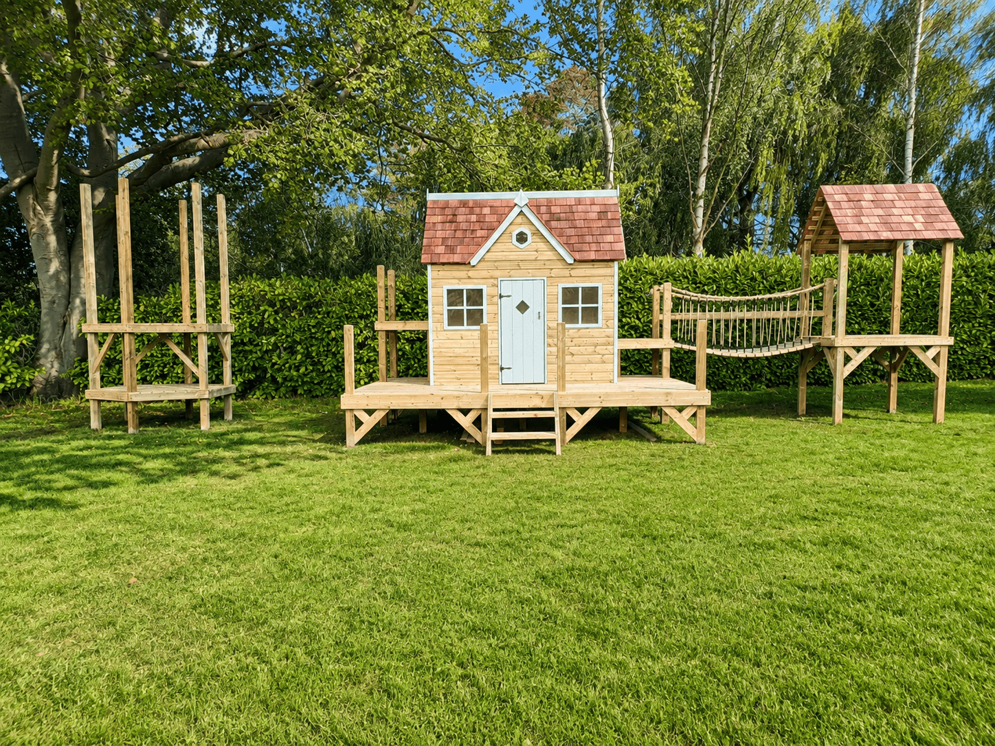 A Forest estate mid-extension: a bare tower frame stands ready beside the finished playhouse and bridge